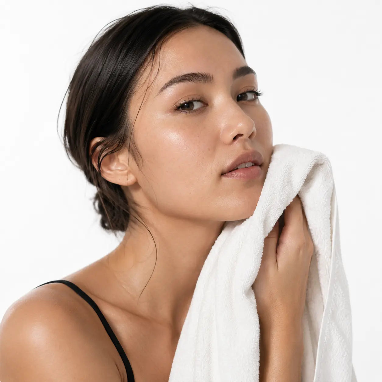 Femme nettoyant son visage avec une serviette, étape essentielle avant l'application du stick EFFAZE